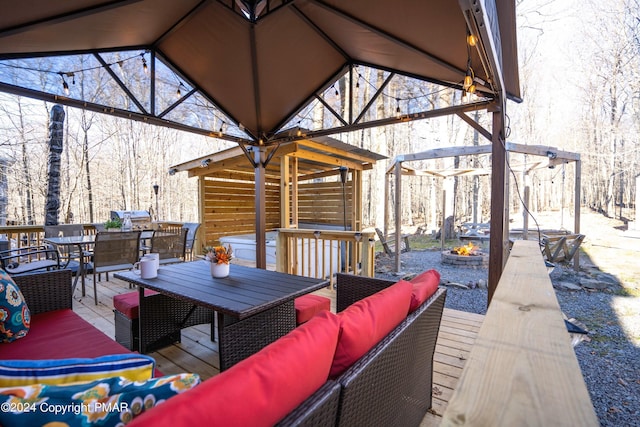 wooden deck featuring outdoor dining area and an outdoor living space with a fire pit