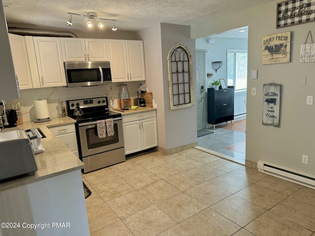 kitchen with backsplash, a textured ceiling, baseboard heating, white cabinets, and stainless steel appliances