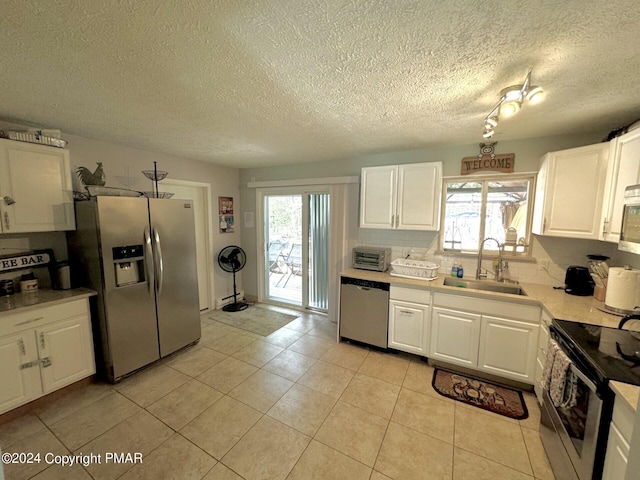 kitchen featuring white cabinets, a textured ceiling, appliances with stainless steel finishes, and a sink
