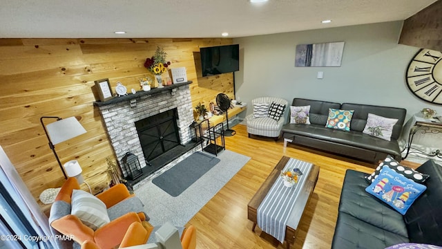 living room featuring wooden walls, a fireplace, recessed lighting, and wood finished floors