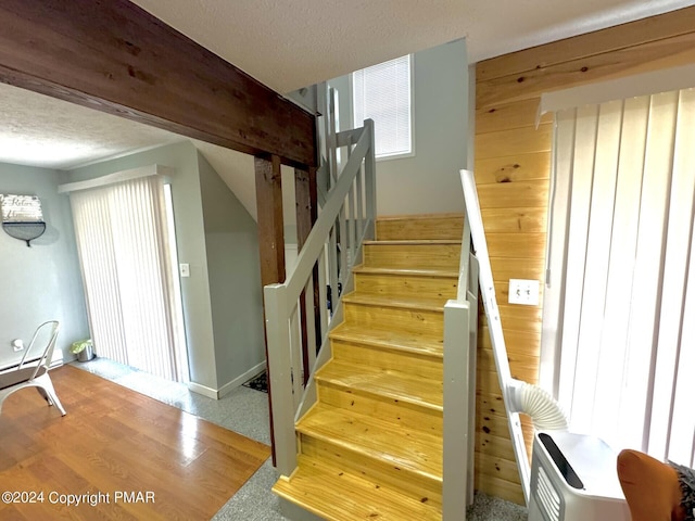 stairway featuring wood walls, a textured ceiling, and wood finished floors