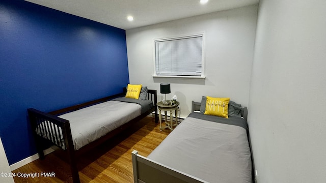 bedroom featuring recessed lighting, baseboards, wood finished floors, and a baseboard radiator