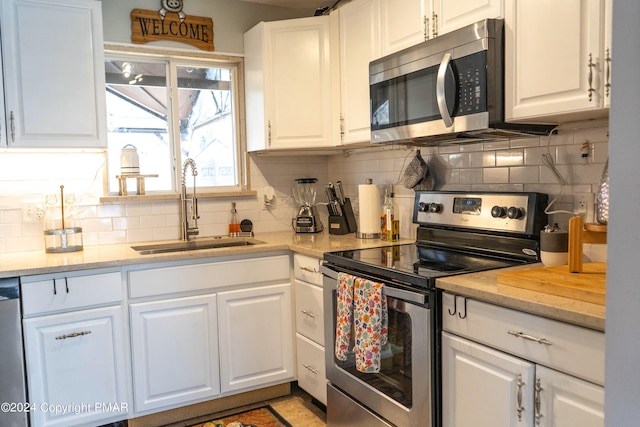 kitchen featuring a sink, appliances with stainless steel finishes, and white cabinets