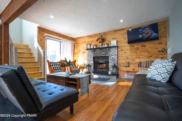 living area with wood finished floors, a fireplace, wooden walls, stairway, and recessed lighting