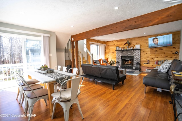 dining room featuring stairs, wooden walls, beam ceiling, and wood finished floors
