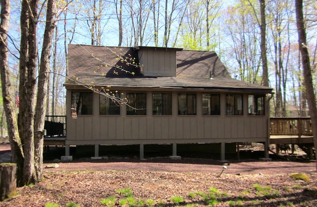 rear view of property with roof with shingles and a deck