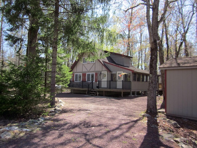 back of property with a wooden deck, an outdoor structure, and a shed