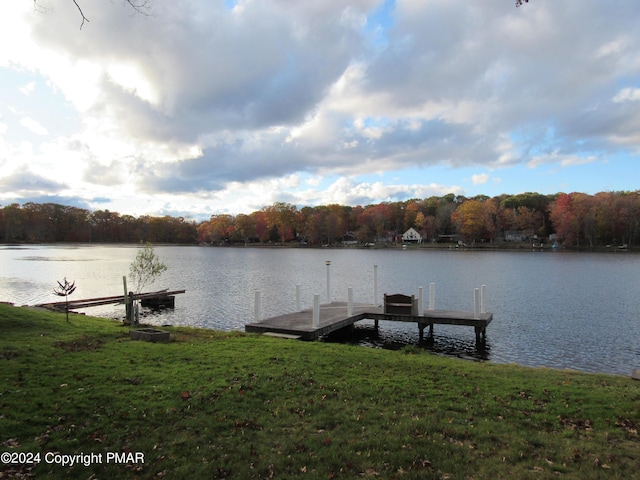 view of dock featuring a water view, a lawn, and a forest view