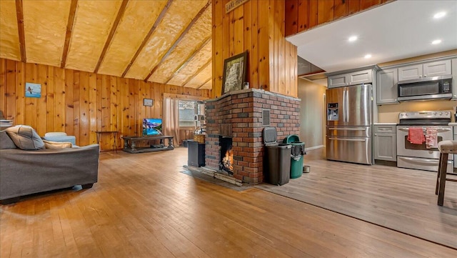 300 Indian Lake Trl, White Haven, PA 18661 - living room with light wood-style floors, wood walls, vaulted ceiling, and a brick fireplace