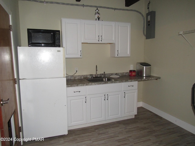 kitchen with black microwave, a sink, white cabinets, freestanding refrigerator, and electric panel