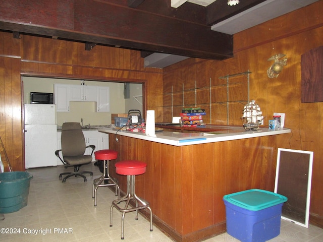 bar with wood walls, black microwave, beam ceiling, and freestanding refrigerator