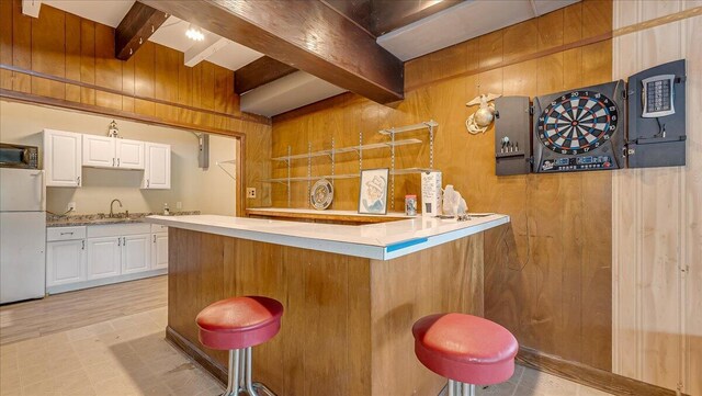 300 Indian Lake Trl, White Haven, PA 18661 - kitchen featuring freestanding refrigerator, beamed ceiling, wood walls, a sink, and white cabinets
