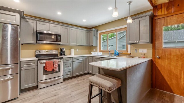 300 Indian Lake Trl, White Haven, PA 18661 - kitchen featuring appliances with stainless steel finishes, gray cabinetry, a peninsula, light wood-style floors, and a kitchen breakfast bar