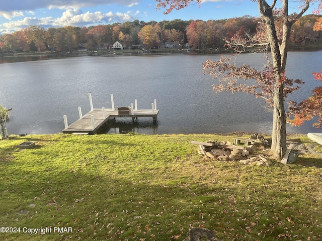 dock area with a water view, a wooded view, and a yard