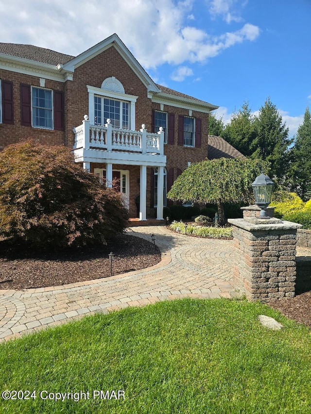 colonial home with a balcony and brick siding