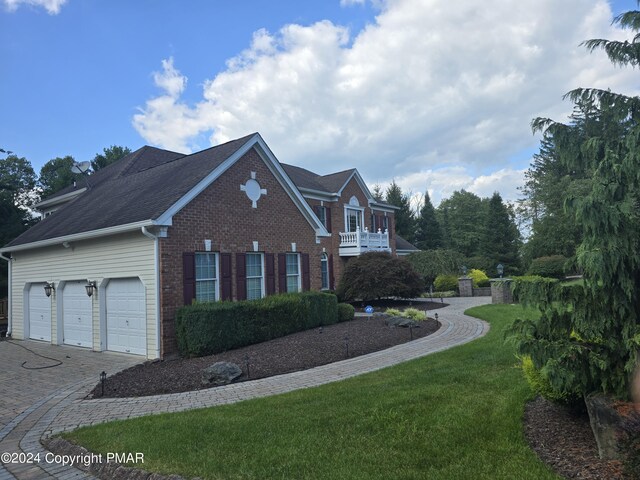 view of side of property with a garage, decorative driveway, a lawn, and brick siding