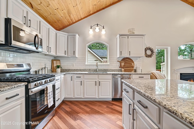 kitchen with white cabinets, wooden ceiling, light wood-style flooring, stainless steel appliances, and a sink