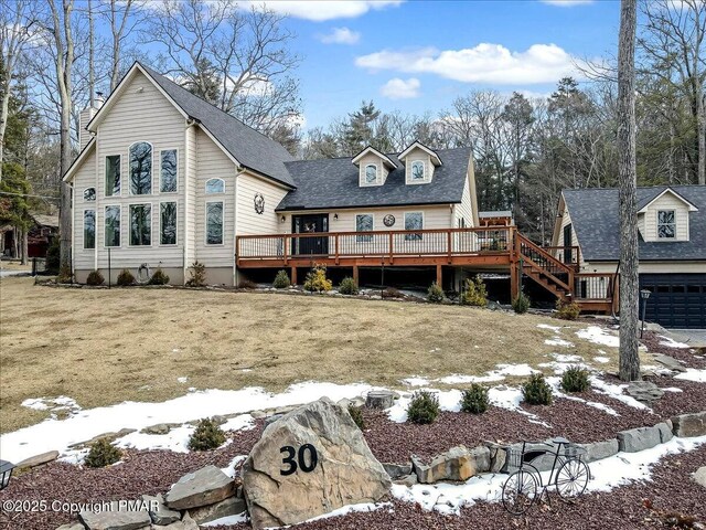 snow covered rear of property featuring a wooden deck and a yard