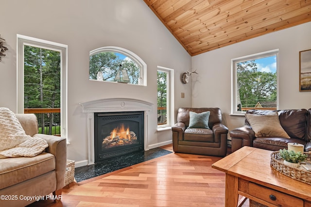 living room with a high end fireplace, wood ceiling, plenty of natural light, and wood finished floors