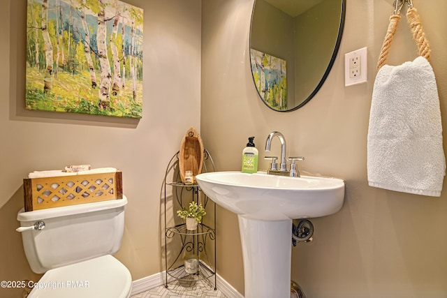 bathroom featuring toilet, baseboards, and a sink