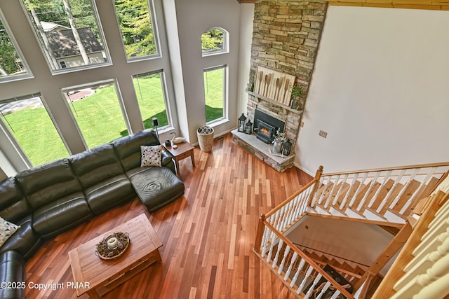 living room with a towering ceiling, stairs, a fireplace, and wood finished floors