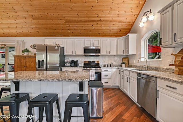 kitchen featuring appliances with stainless steel finishes, a wealth of natural light, wood ceiling, and a sink