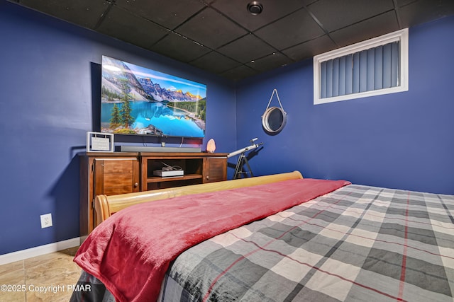 bedroom featuring a paneled ceiling and baseboards