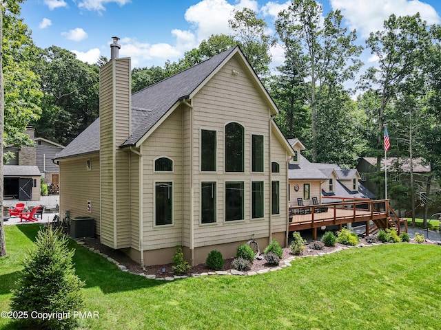 rear view of property featuring a deck, a lawn, a chimney, and a shingled roof