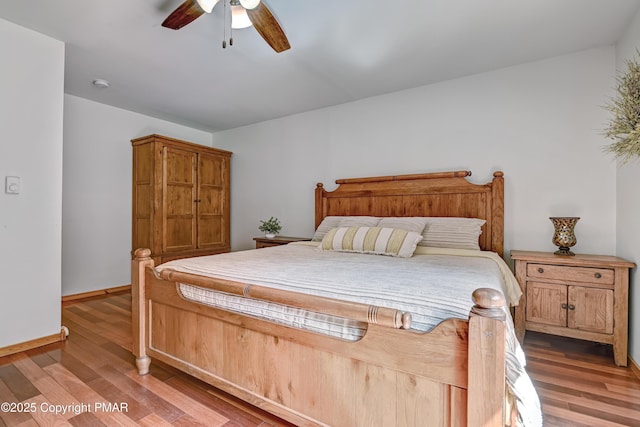 bedroom with a ceiling fan, baseboards, and wood finished floors