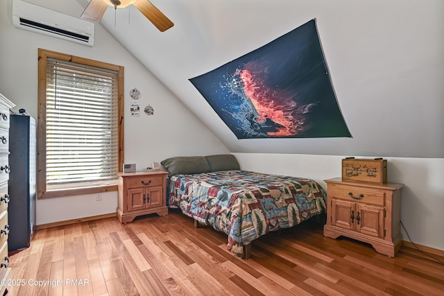 bedroom featuring ceiling fan, lofted ceiling, a wall mounted AC, and light hardwood / wood-style floors