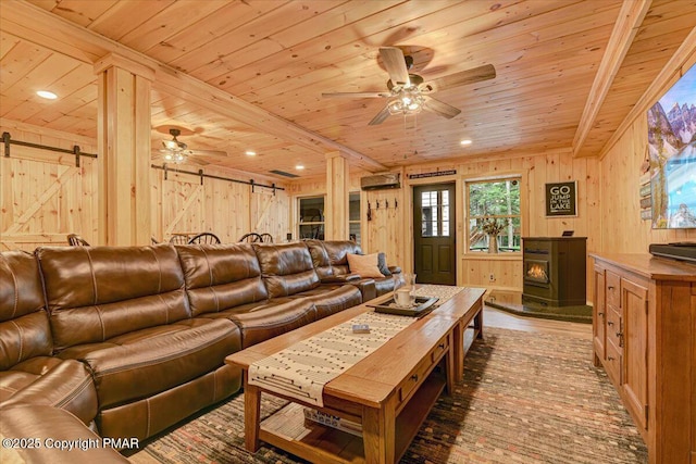 living area featuring wooden ceiling, a barn door, a ceiling fan, and wood walls