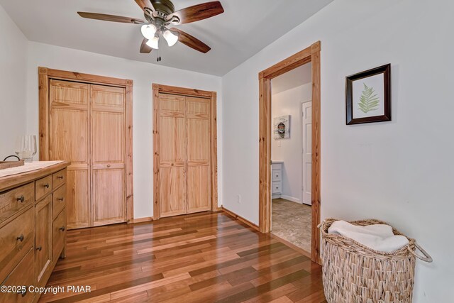 bedroom with hardwood / wood-style floors, multiple closets, and ceiling fan