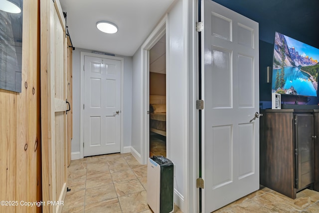 hall with baseboards and a barn door