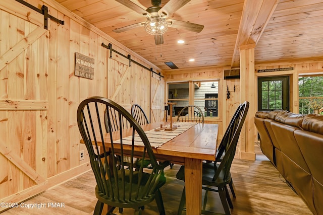 dining room with wood finished floors, wood ceiling, wood walls, and a barn door