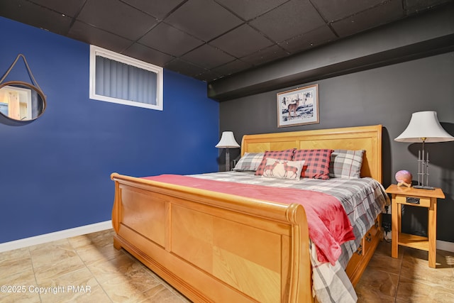 bedroom featuring a paneled ceiling and baseboards