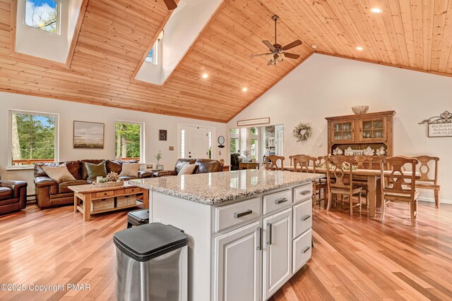 kitchen featuring a kitchen island, high vaulted ceiling, white cabinetry, wood ceiling, and light hardwood / wood-style floors