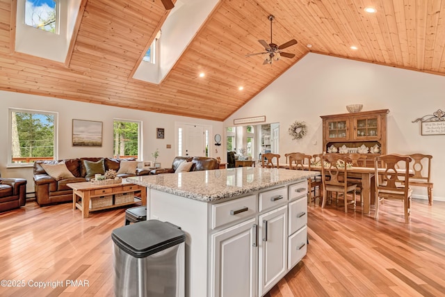 kitchen featuring high vaulted ceiling, wooden ceiling, open floor plan, a center island, and light wood finished floors