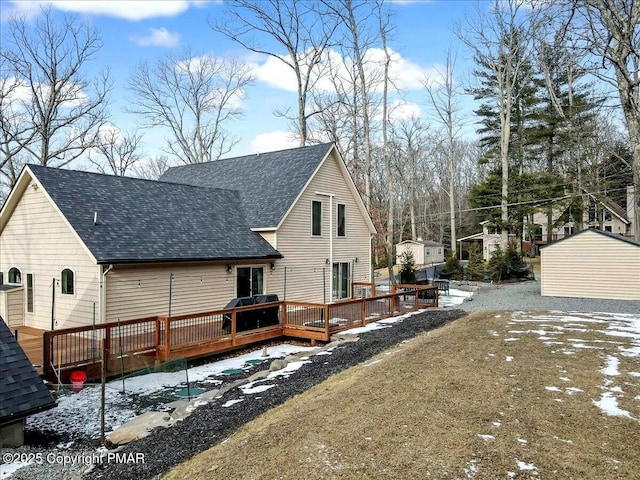 back of property featuring a shingled roof and a wooden deck