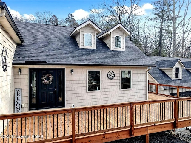 property entrance with roof with shingles and a wooden deck