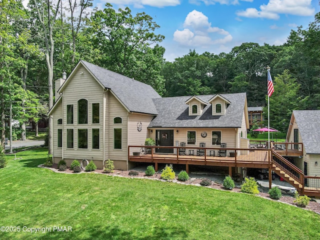 rear view of property with roof with shingles, a lawn, and a wooden deck