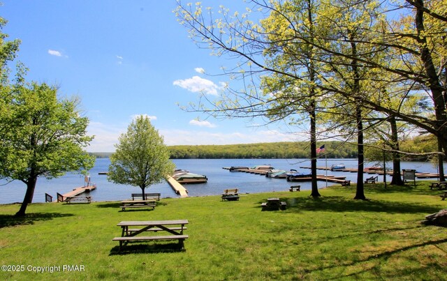 surrounding community with a water view and a lawn