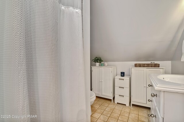 bathroom featuring vanity, lofted ceiling, tile patterned floors, and toilet