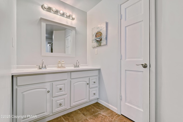 full bathroom featuring double vanity, baseboards, and a sink