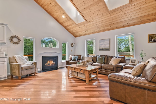 living area with light wood finished floors, a skylight, a fireplace with flush hearth, and wooden ceiling