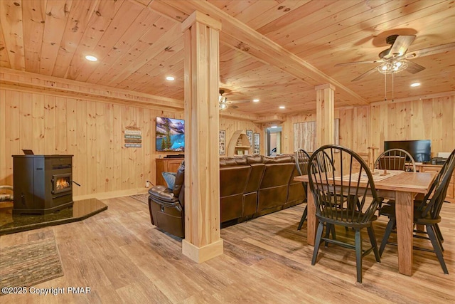 dining area with a wood stove, light wood finished floors, wood ceiling, and a ceiling fan