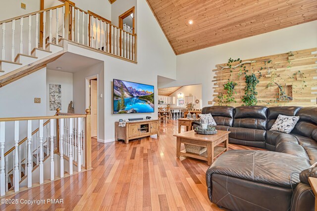 living room with wooden ceiling, a high ceiling, and light wood-type flooring