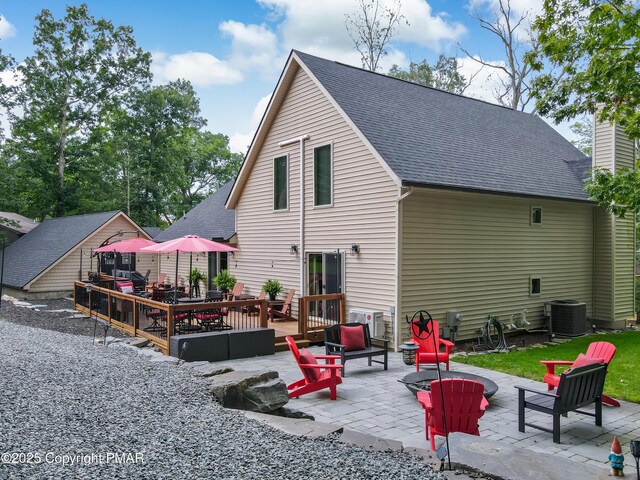 rear view of house featuring cooling unit, a storage unit, an outdoor fire pit, and a patio area