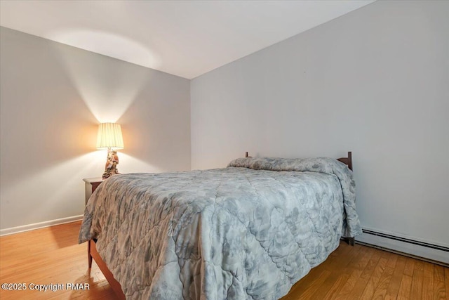 bedroom with wood-type flooring and a baseboard heating unit