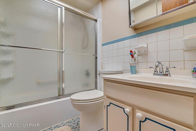 full bathroom with toilet, vanity, bath / shower combo with glass door, and tile walls