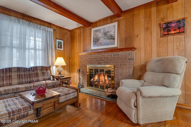 living room with hardwood / wood-style floors, a fireplace, beam ceiling, and wood walls